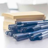ein Stapel gelber Post-Its neben einem Haufen blauer Stifte
